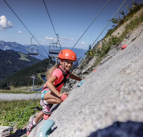 Kletterspaß in Spieljoch ©Erste Ferienregion im Zillertal, Andi Frank Mädchen klettert an einer Felswand mit Helm und Sportausrüstung.