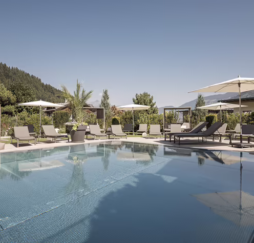 Außenpool mit Sonnenterrasse im Hotel Platzlhof Großzügiger Außenpool des Hotel Platzlhof mit Sonnenliegen, Daybeds und Blick auf die Zillertaler Bergwelt.